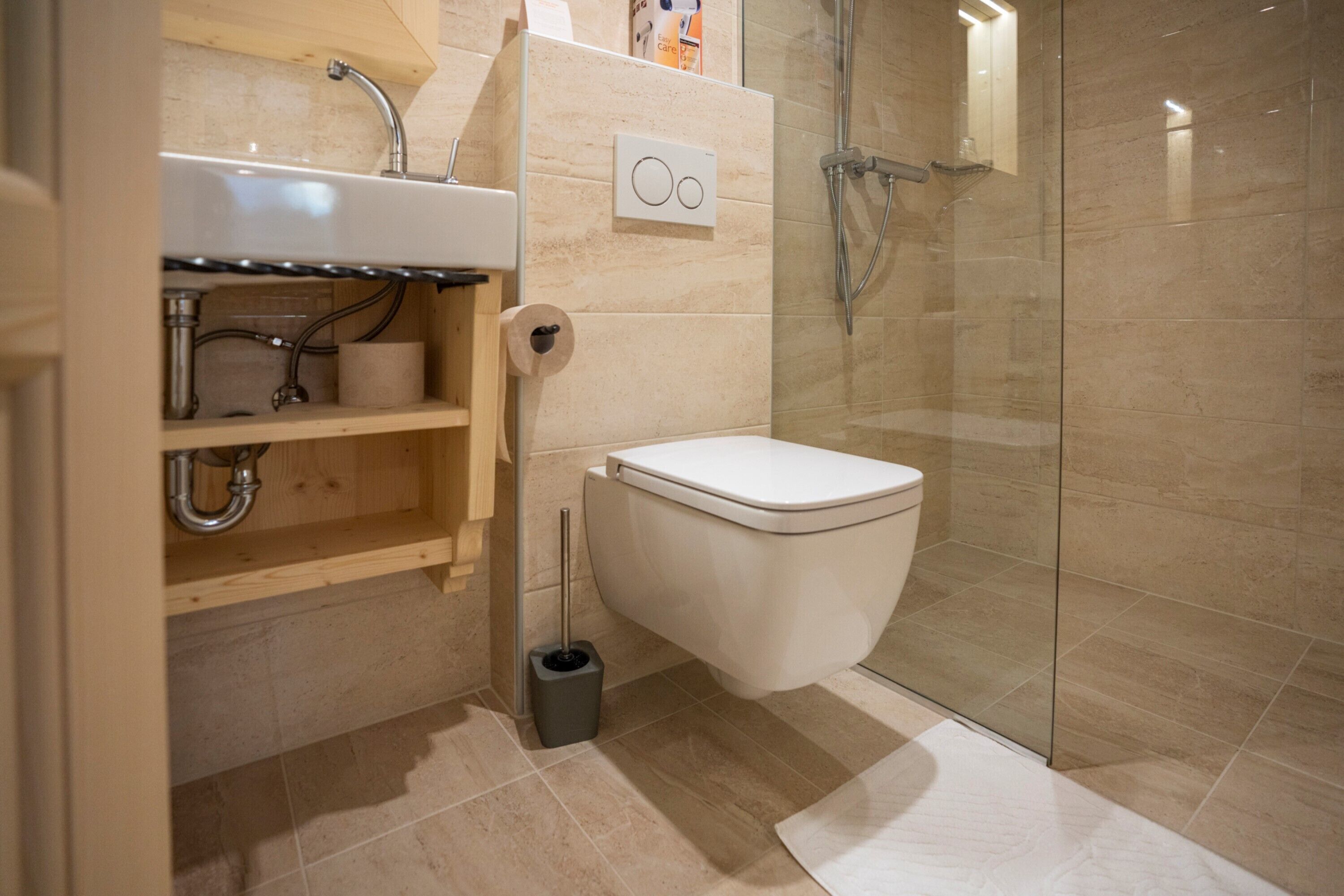 A modern bathroom with a glass-enclosed shower, a white toilet, and a wooden vanity with a sink.
