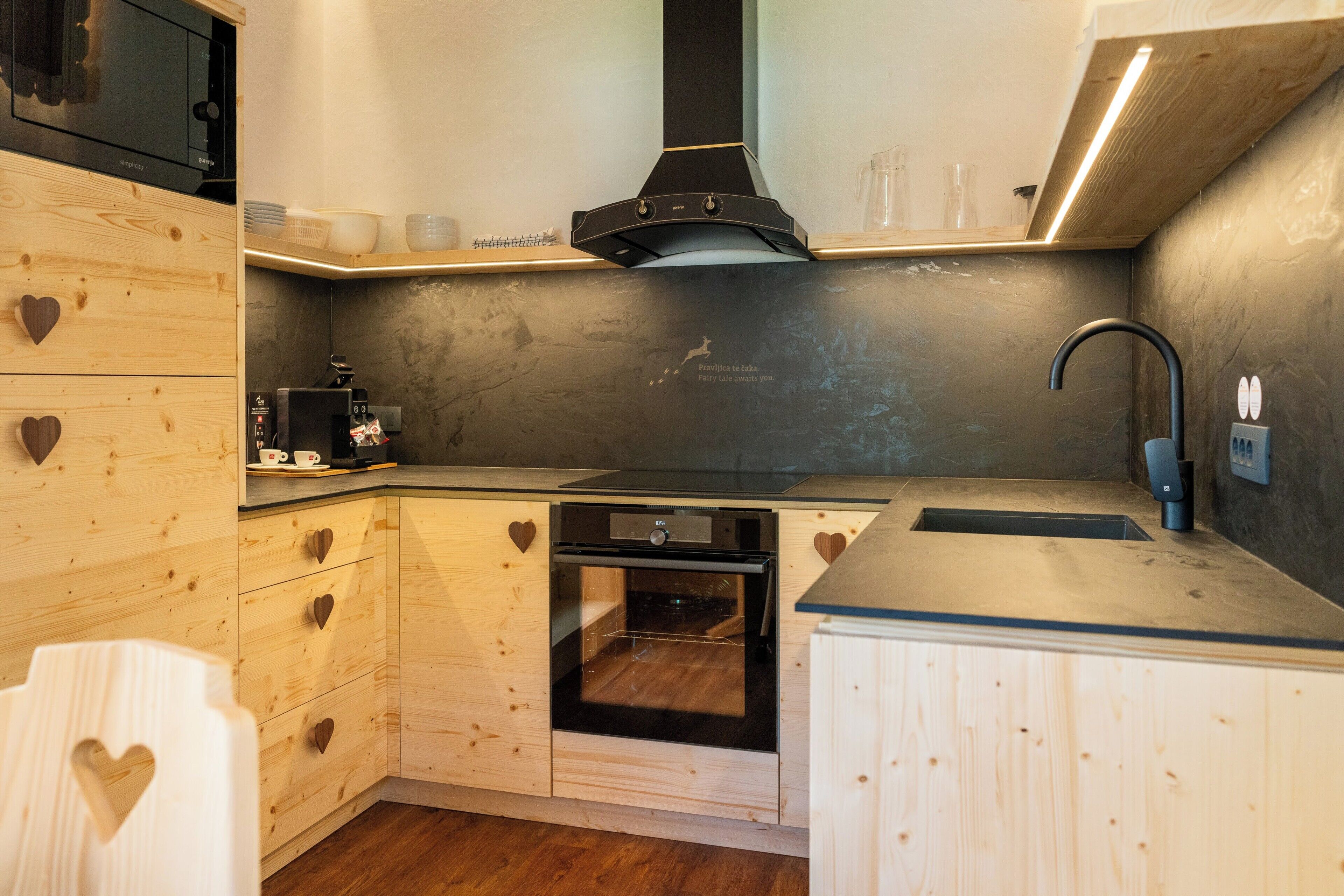 A compact kitchen with wooden cabinetry, a built-in oven, a microwave, and a sink.