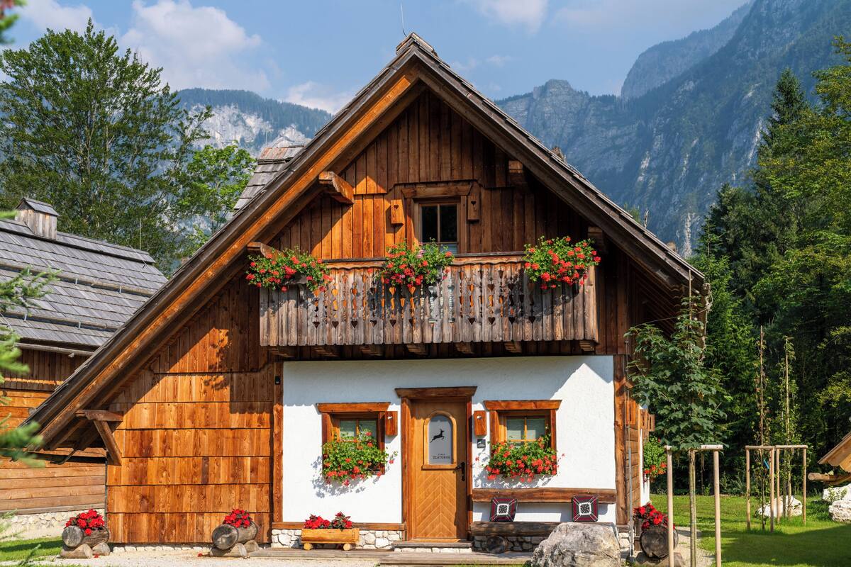 A wooden chalet with a balcony, stone steps, and flower boxes.