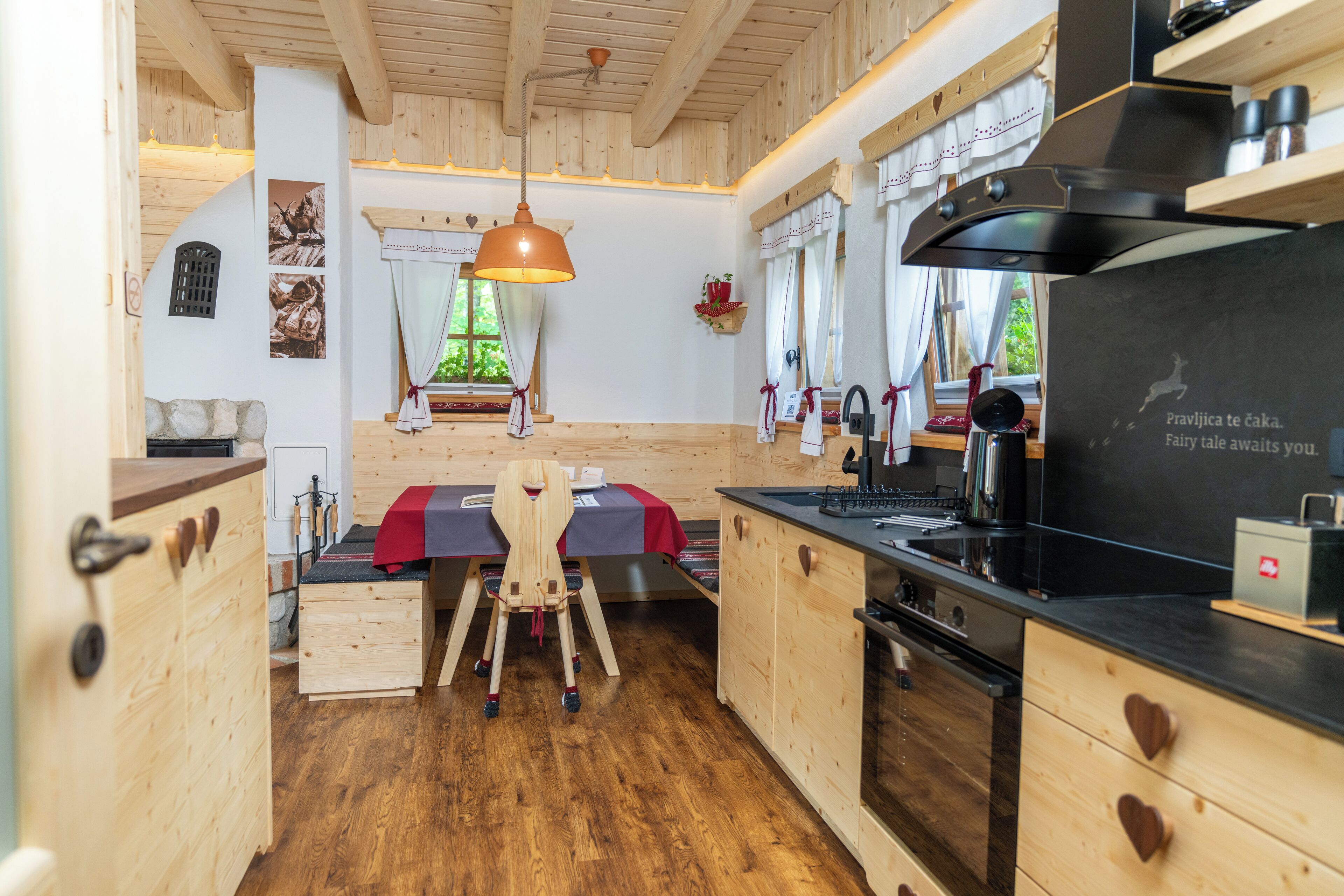 Eine gemütliche Küche mit Holzschränken, einem Holztisch und einer Pendelleuchte.