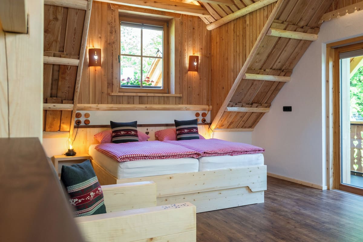 A loft-style bedroom with a sloped ceiling, a large window, and a built-in bed.