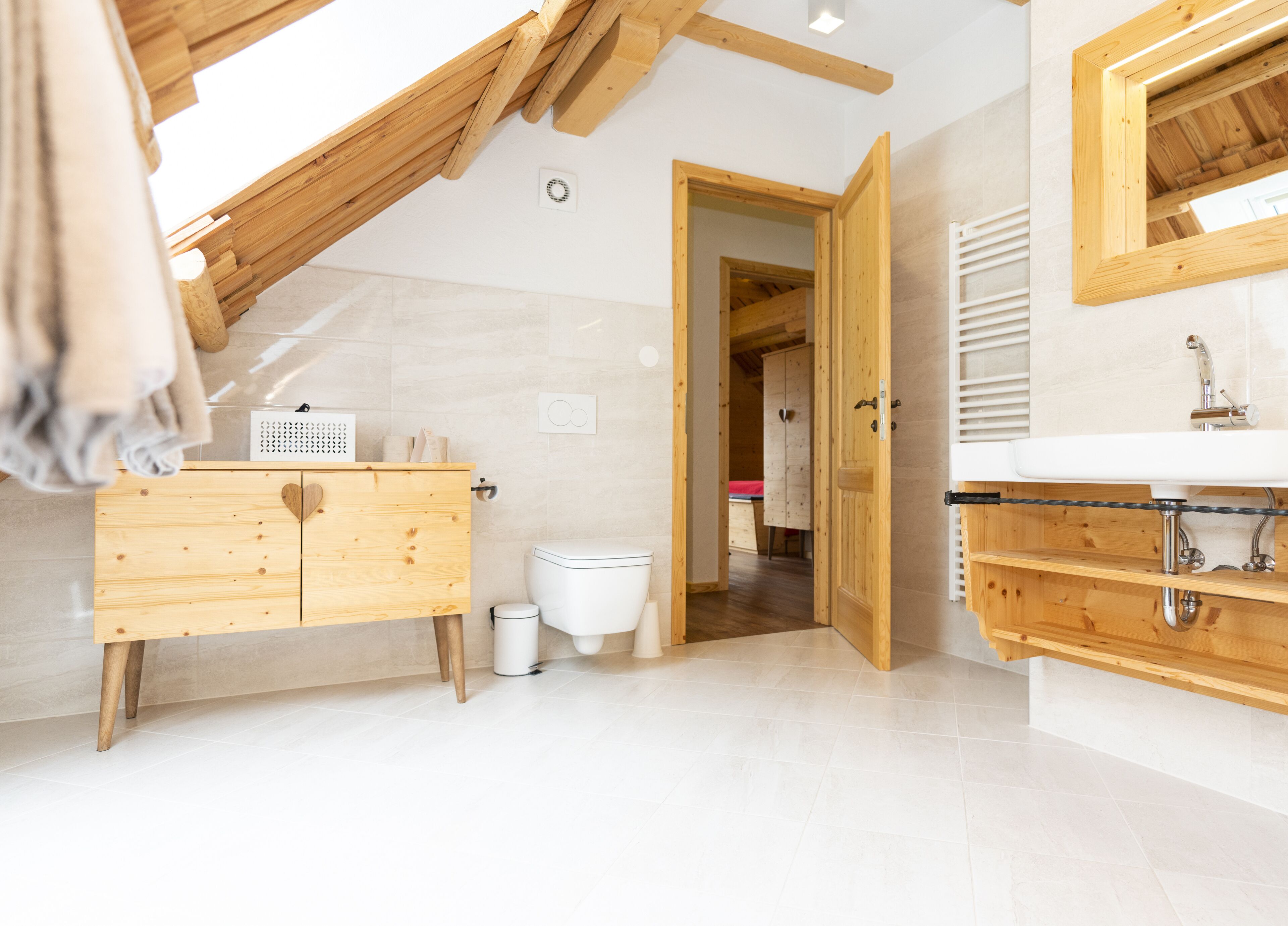 Un baño moderno con tocador de madera, inodoro blanco y zona de ducha.