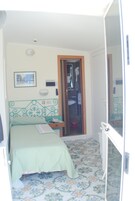 A bedroom with a bed, bedside table, and a bathroom visible through an open door.