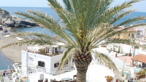 A rooftop bar with outdoor seating, a palm tree, and a view of the beach and ocean. - Hotel La Palma (Serrara Fontana)