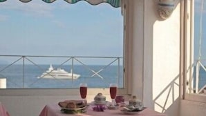 A balcony with a table set for two, overlooking the sea and a yacht. - Hotel La Palma (Serrara Fontana)