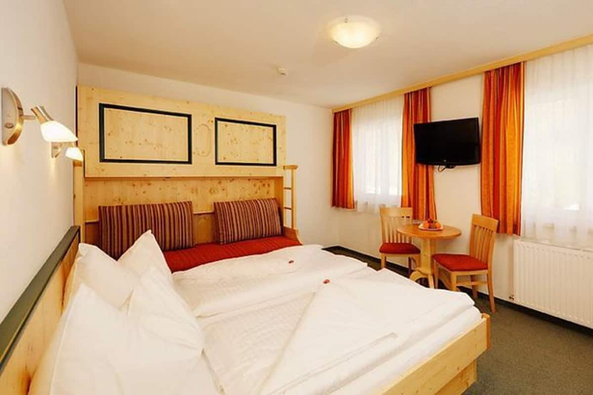 Une chambre d’hôtel équipée d’un lit, d’un bureau, d’une chaise, d’une télévision et d’une fenêtre avec des rideaux.