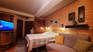 Una habitación acogedora con una cama, un sofá, un televisor y paredes de madera.