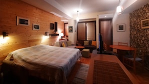 Una habitación acogedora con cama, un pequeño rincón de descanso, televisor y una mesa de comedor.