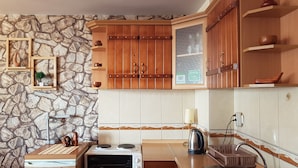 Una cocina con pared de piedra, armarios de madera, una estufa y un hervidor.