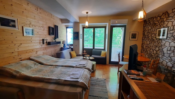 Una habitación acogedora con dos camas, un sofá, una mesa de comedor y una pared de piedra.