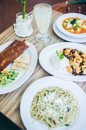 A table with various dishes including a fish dish, rice with shrimp, and pasta. - Hotel Jaragua (Boca del Río)