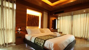Een ruime slaapkamer met een groot bed, houten paneelwanden en een moderne lamp boven het bed.