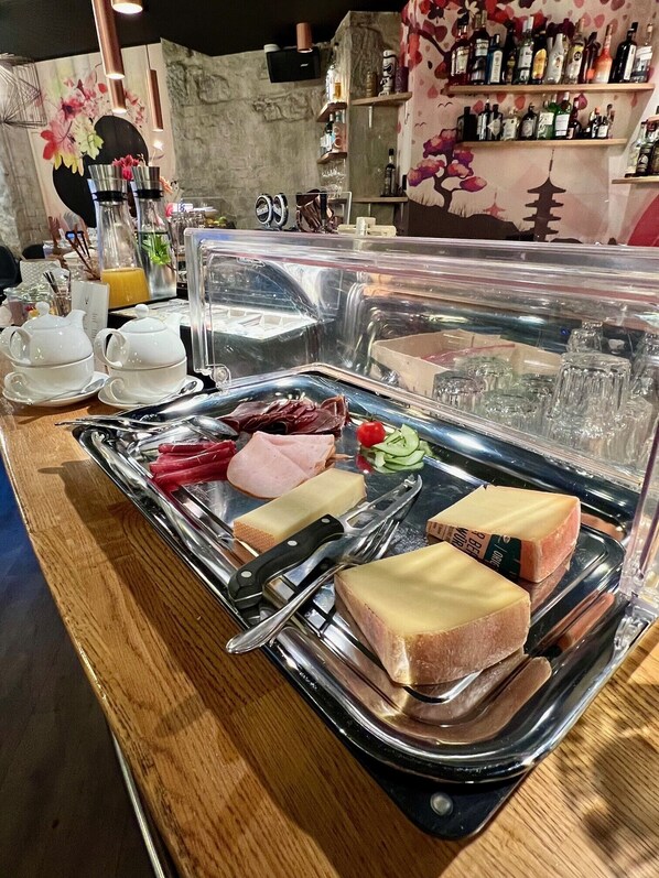 Un bufé de desayuno con diferentes alimentos, utensilios y una exhibición de bebidas.
