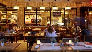 A restaurant with wooden tables and benches, stone walls, and hanging pendant lights. - Löwenhof (Varna)