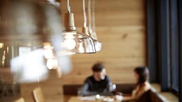 Interior de restaurante con paredes de madera, lámparas colgantes y una persona sentada en una mesa.