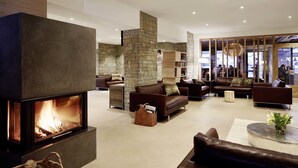 A modern living room with a stone fireplace, leather sofas, and a coffee table. - Löwenhof (Varna)