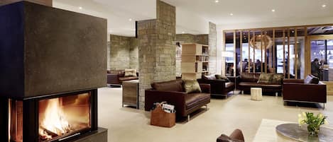 A modern living room with a stone fireplace, leather sofas, and a coffee table.