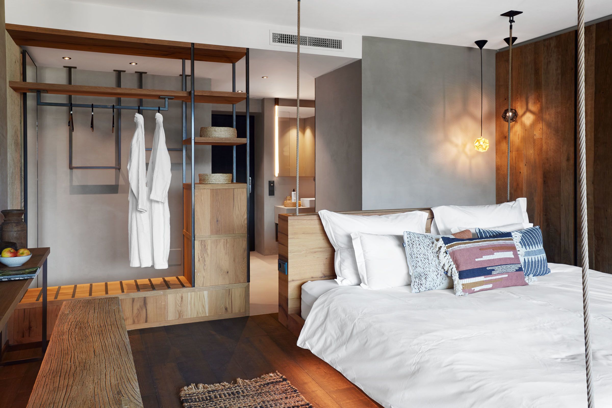 A modern bedroom with a large bed, wooden furniture, and a hanging light fixture.