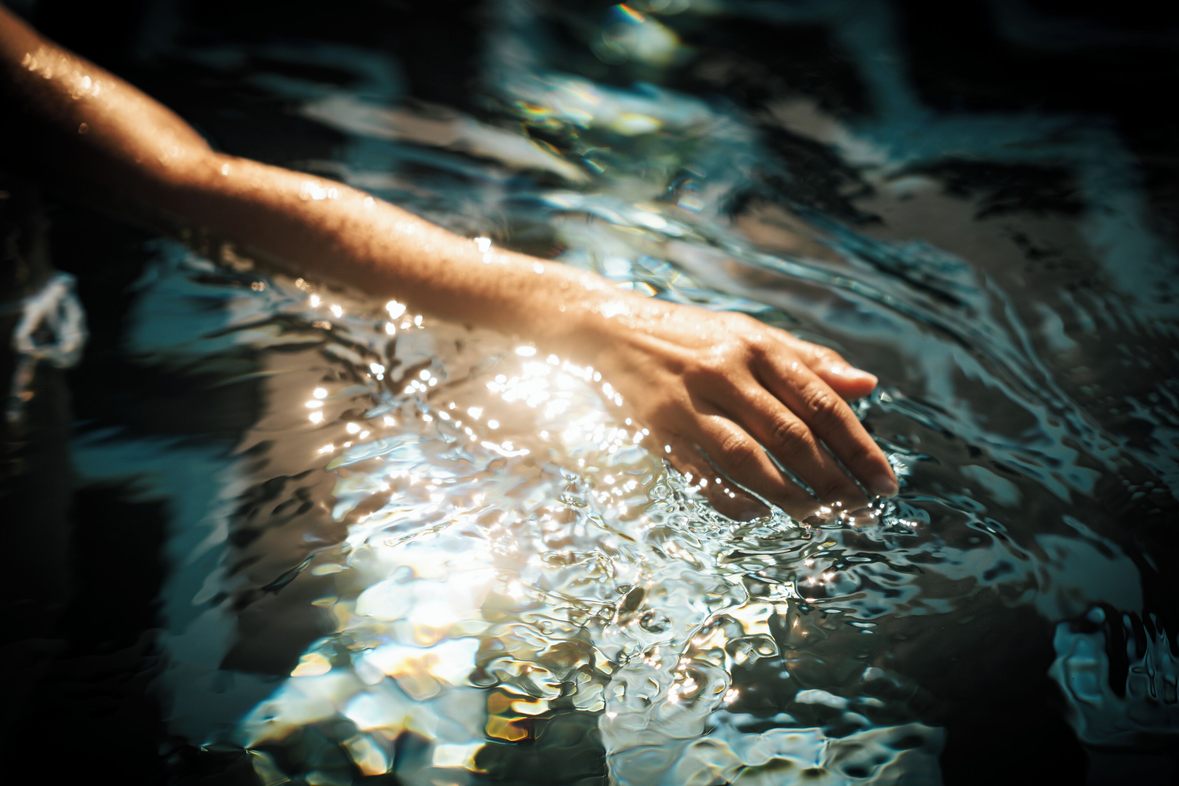Une main qui touche l'eau, créant des ondulations.