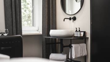 Une salle de bain moderne avec un lavabo blanc, un miroir rond et un porte-serviettes.
