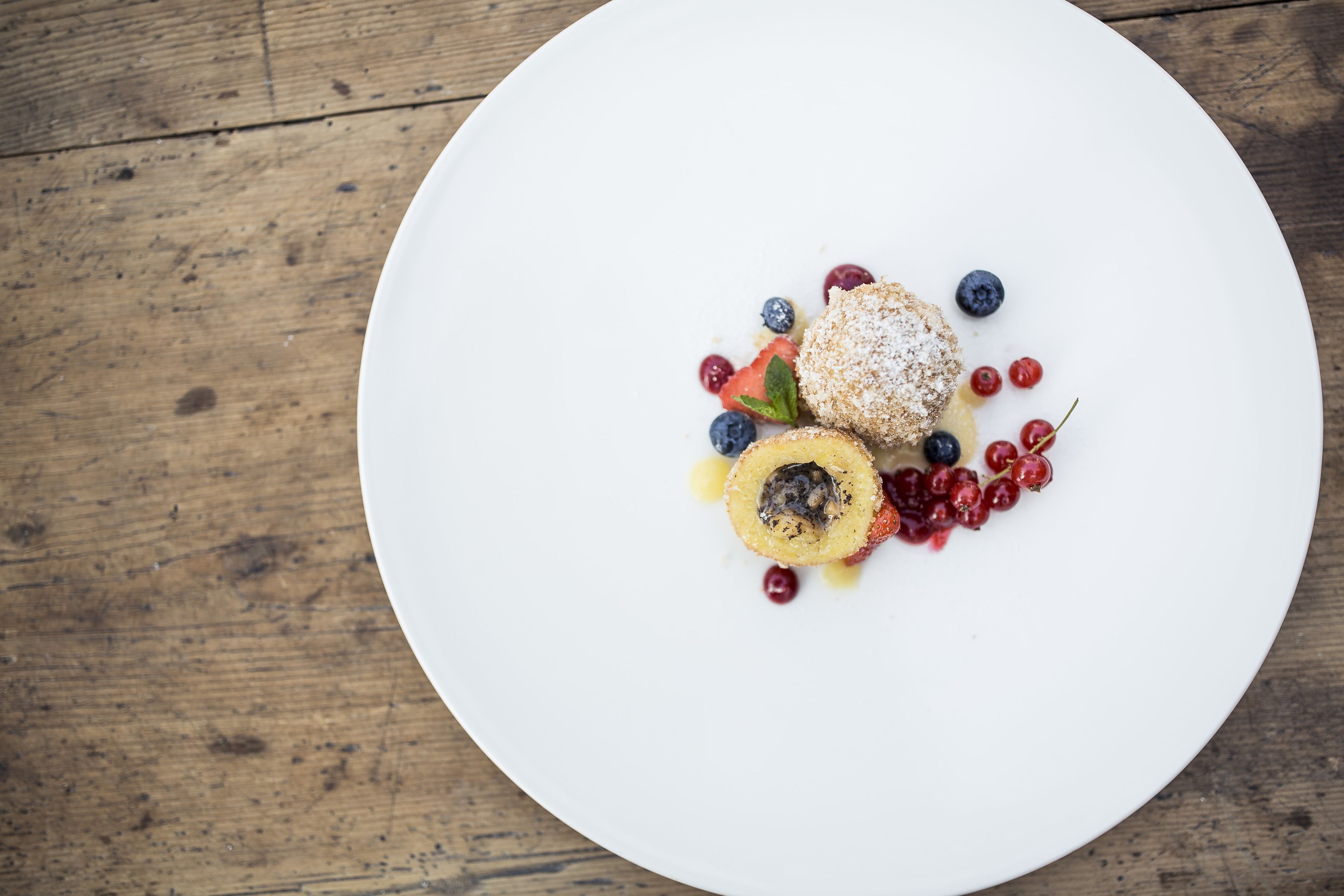 Une assiette blanche avec un dessert posé sur une table en bois.