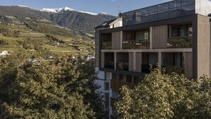 A modern building with a flat roof, large windows, and a balcony overlooking a mountainous landscape. - Löwenhof (Varna)