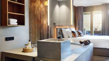 Un baño moderno con un lavamanos grande, estantes de madera y una cama con almohadas.