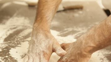 Una persona stende la pasta su un piano infarinato.
