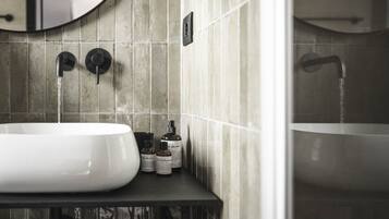 A bathroom with a white sink, two faucets, and a shower.