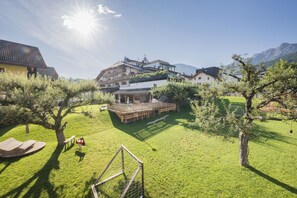 A residential area with a grassy yard, a wooden deck, and a house with a balcony.