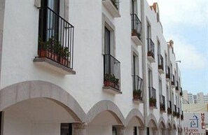 Un hôtel à plusieurs étages, doté de balcons, de fenêtres en arc de cercle et offrant une vue sur un ciel dégagé.