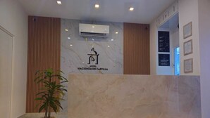 A hotel reception area with a marble reception desk, a potted plant, and an air conditioning unit. - Hotel Hacienda de Castilla (Cancun)