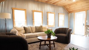 Una sala de estar acogedora con un sofá, un sillón y una mesa de centro redonda de madera con una planta.