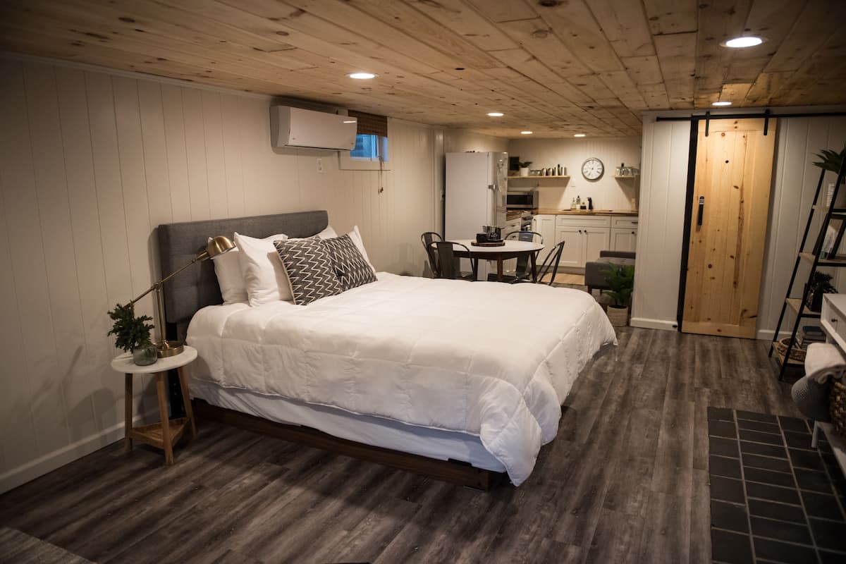 A bedroom with a bed, bedside table, lamp, and a small plant.