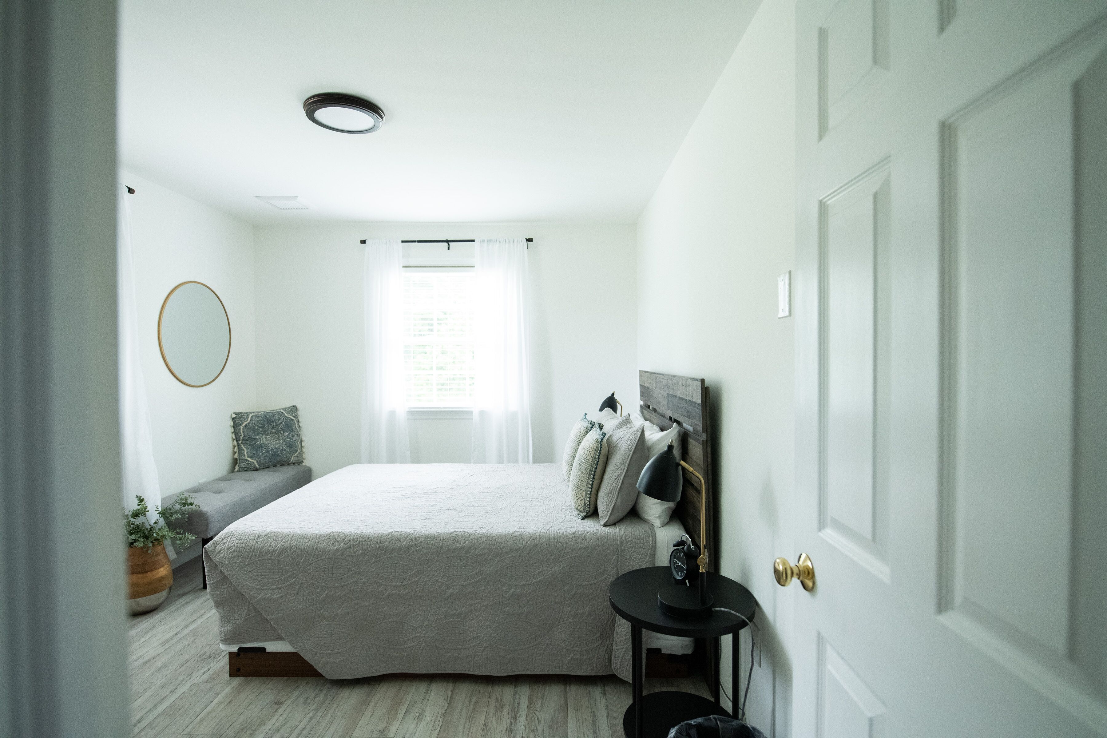 A bedroom with a bed, bedside table, lamp, and a door.