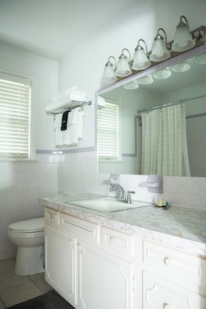 A bathroom with a white sink, mirror, and toilet.