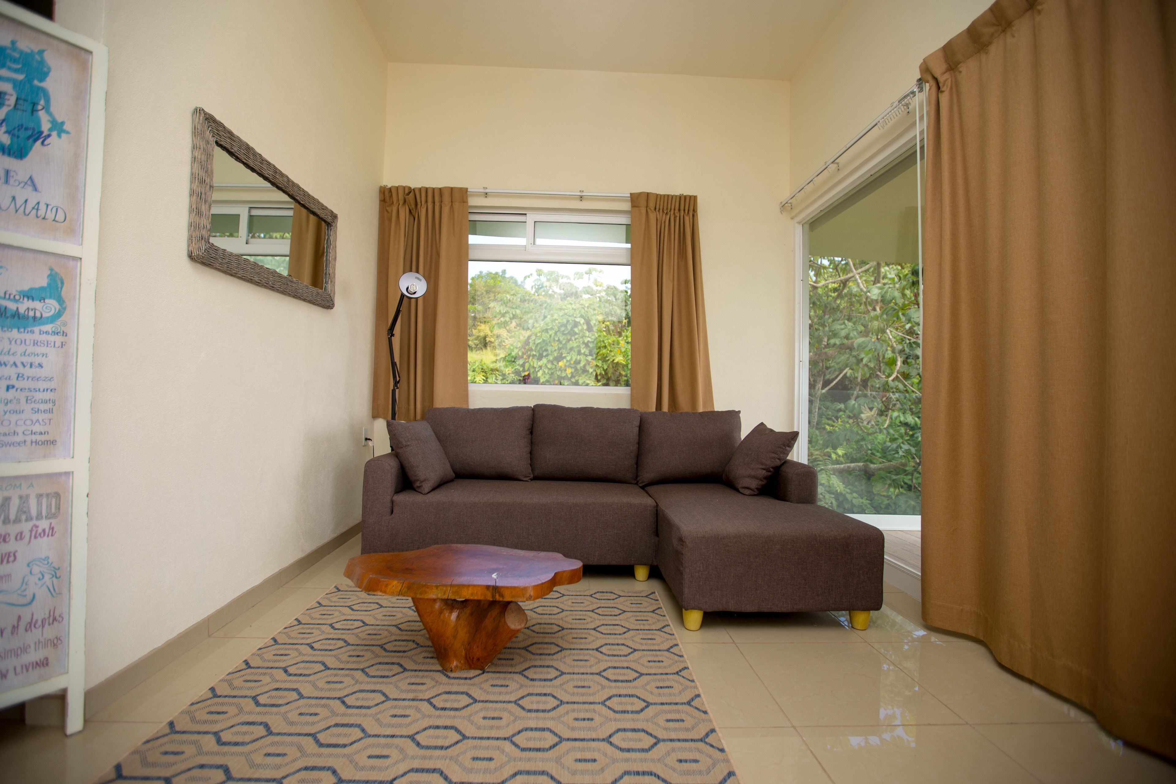 A living room with a brown sectional sofa, a wooden coffee table, and a patterned rug.