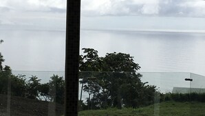 A view of a calm sea through a window with a tiled column in the foreground.