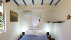 A bedroom with a bed, bedside tables, a nightstand, a window, and a ceiling fan.