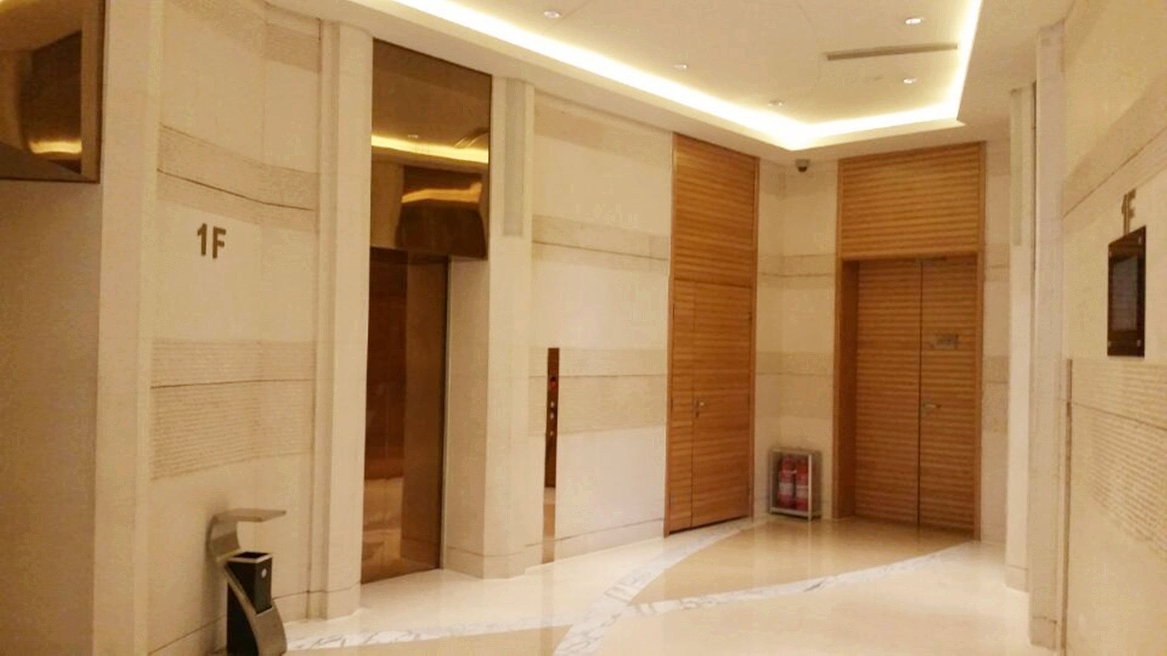 A modern hallway with a polished floor, wooden doors, and a fire extinguisher.