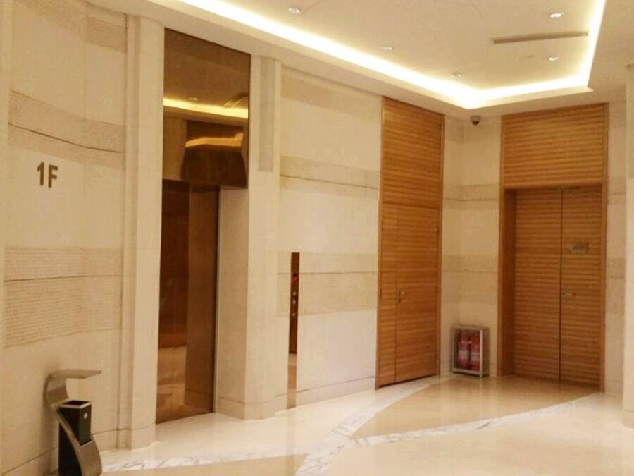 A modern hallway with a polished floor, wooden doors, and a fire extinguisher.
