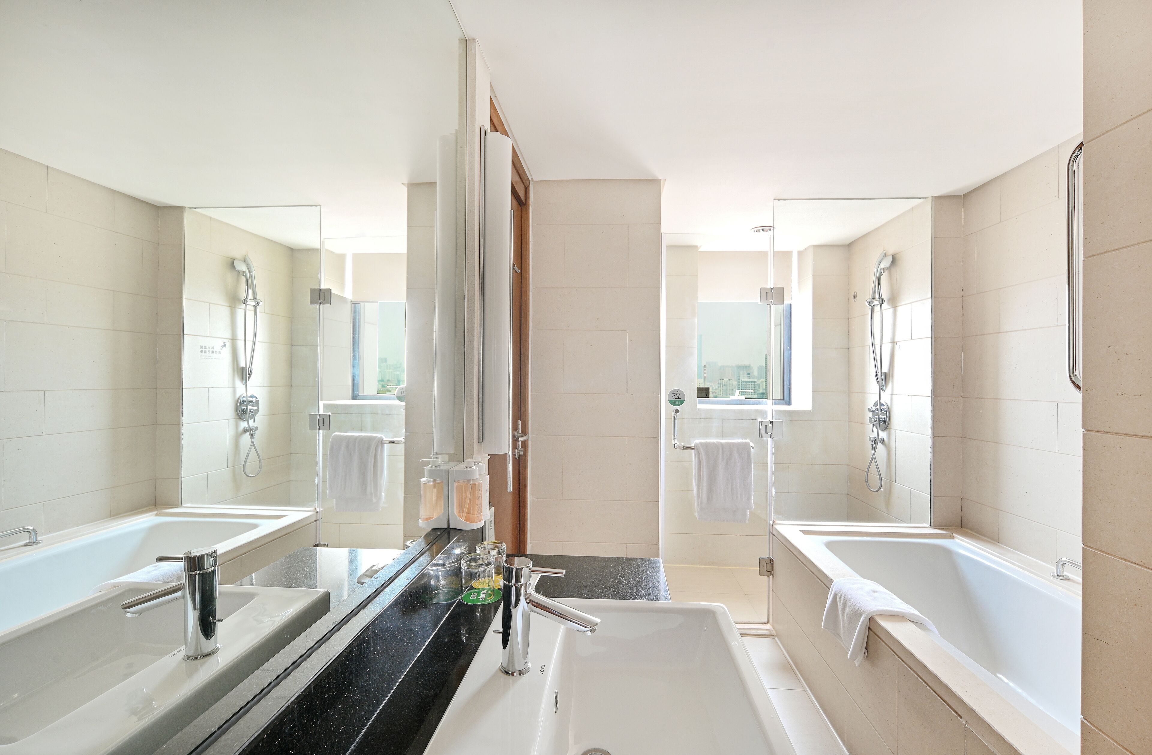 A modern bathroom with two sinks, a bathtub, and a shower.