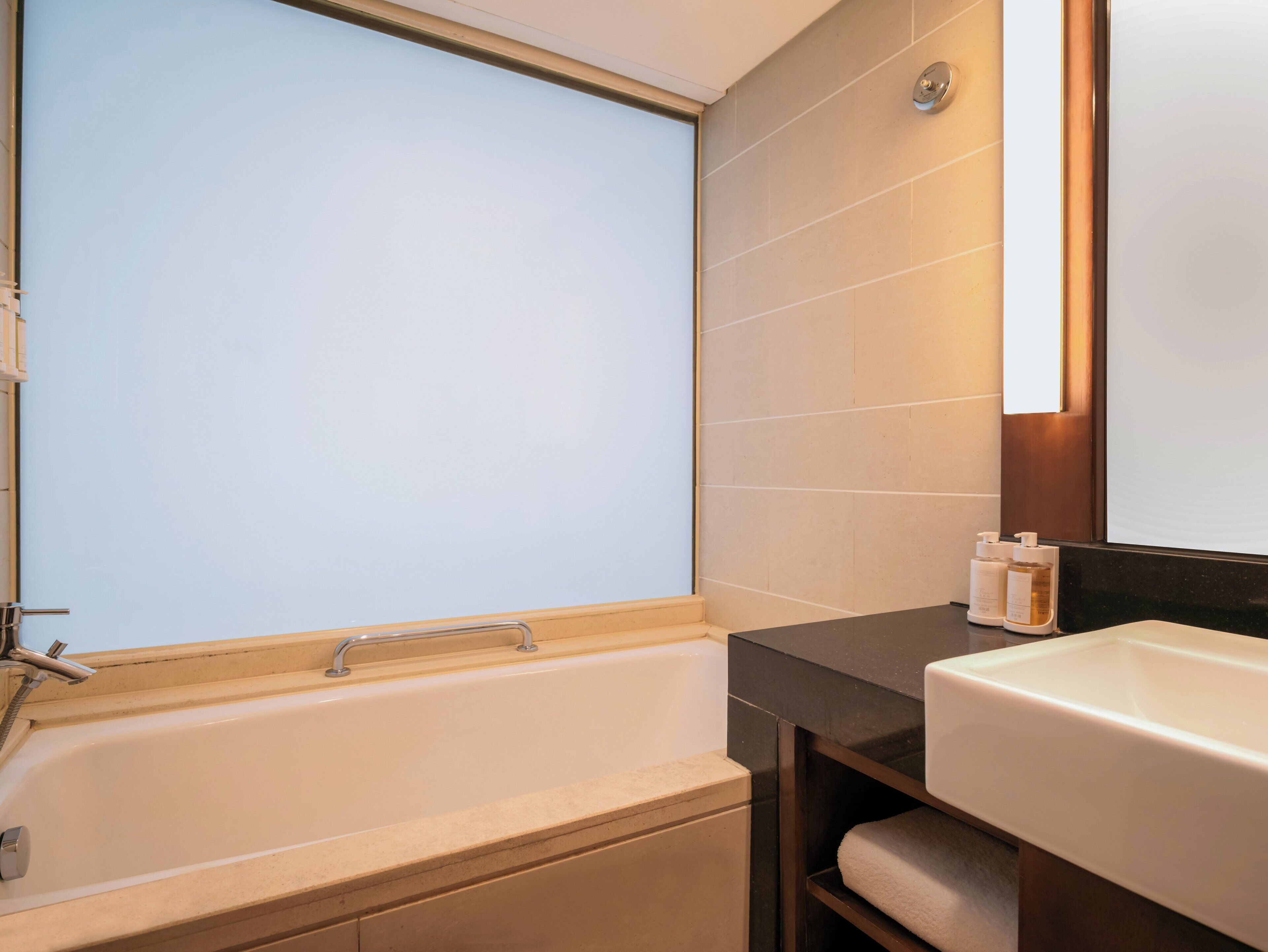 A modern bathroom with a bathtub, a sink, and a mirror.