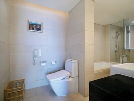 Un baño con inodoro, ducha, lavabo, espejo y un cuadro enmarcado en la pared.