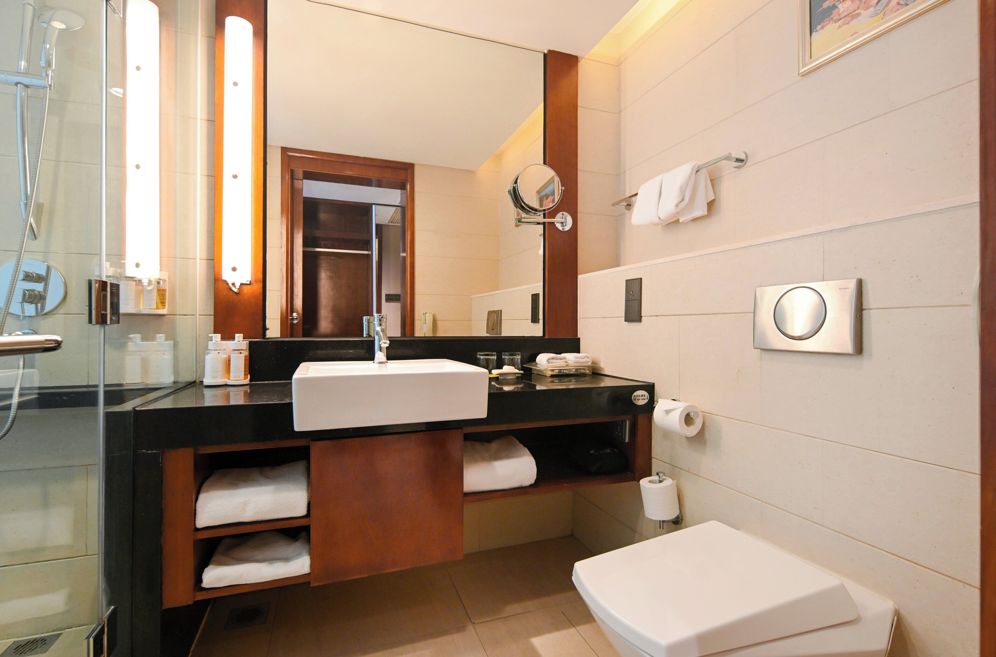 A modern bathroom with a glass-enclosed shower, a sink with a mirror, a toilet, and a towel rack.