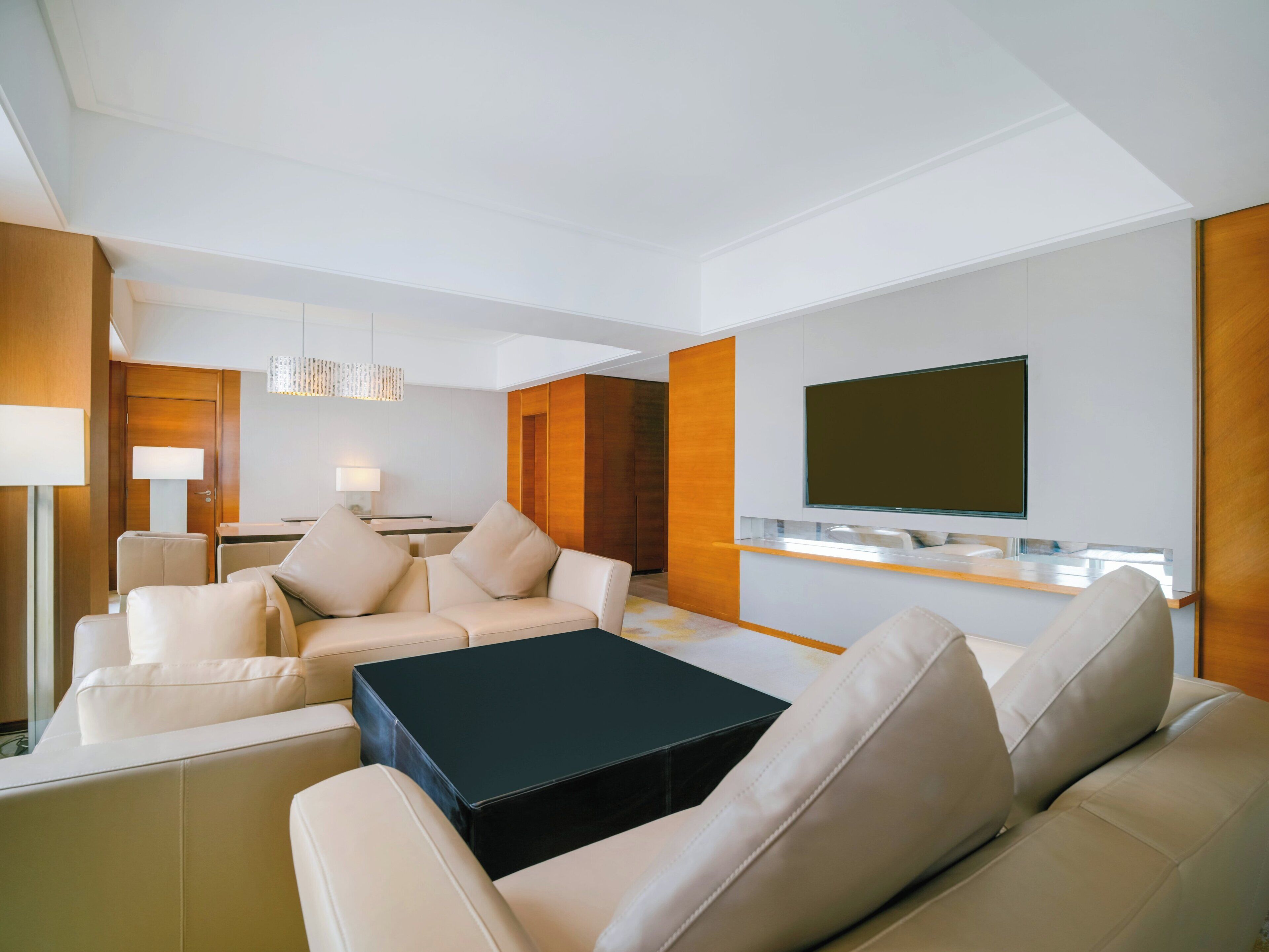 Una sala moderna con un conjunto de sofá, una mesa de centro, un televisor montado en la pared y una pared de acento de madera.