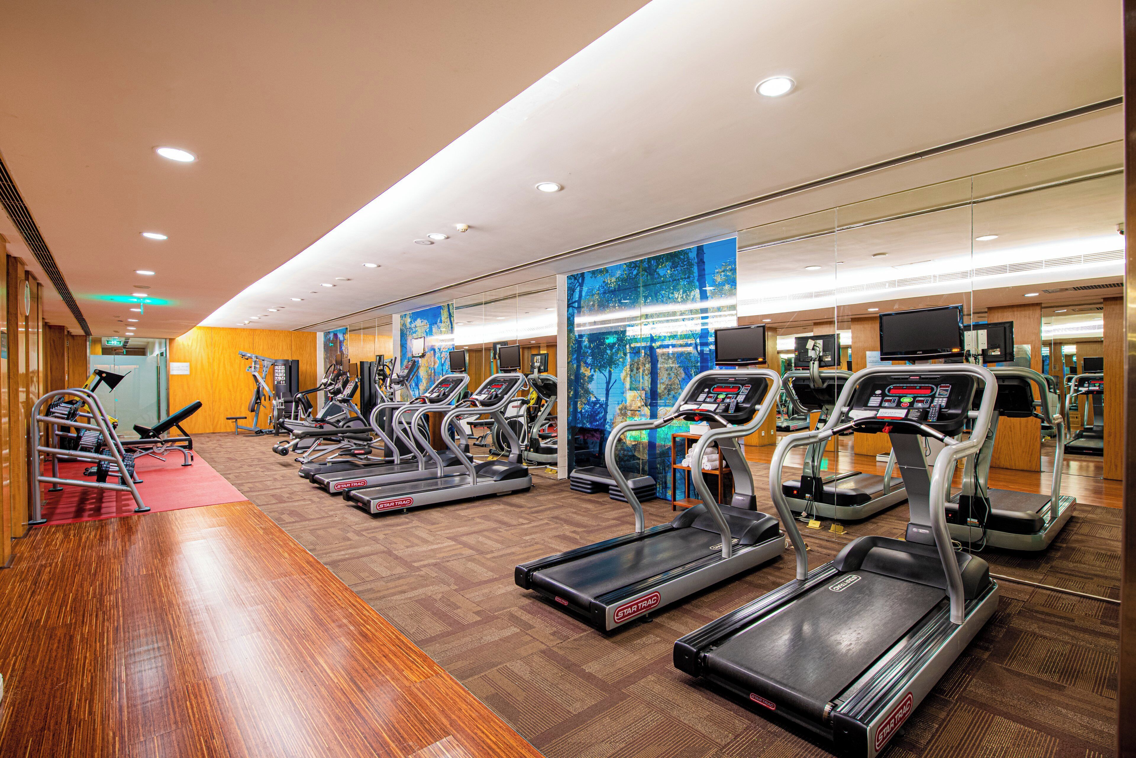A gym with multiple treadmills, weight machines, and a red carpeted area.