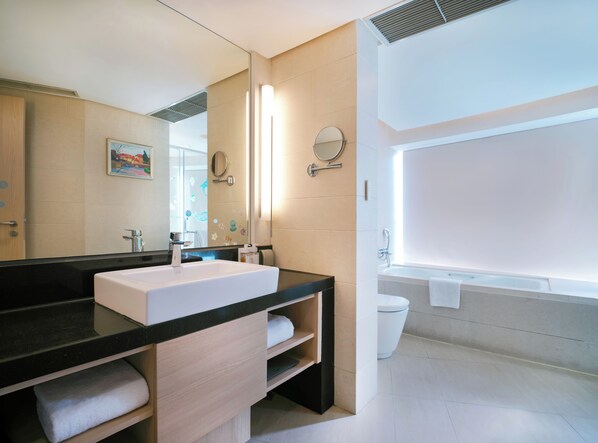 Un baño moderno con un espejo grande, dos lavamanos, una bañera y un inodoro.