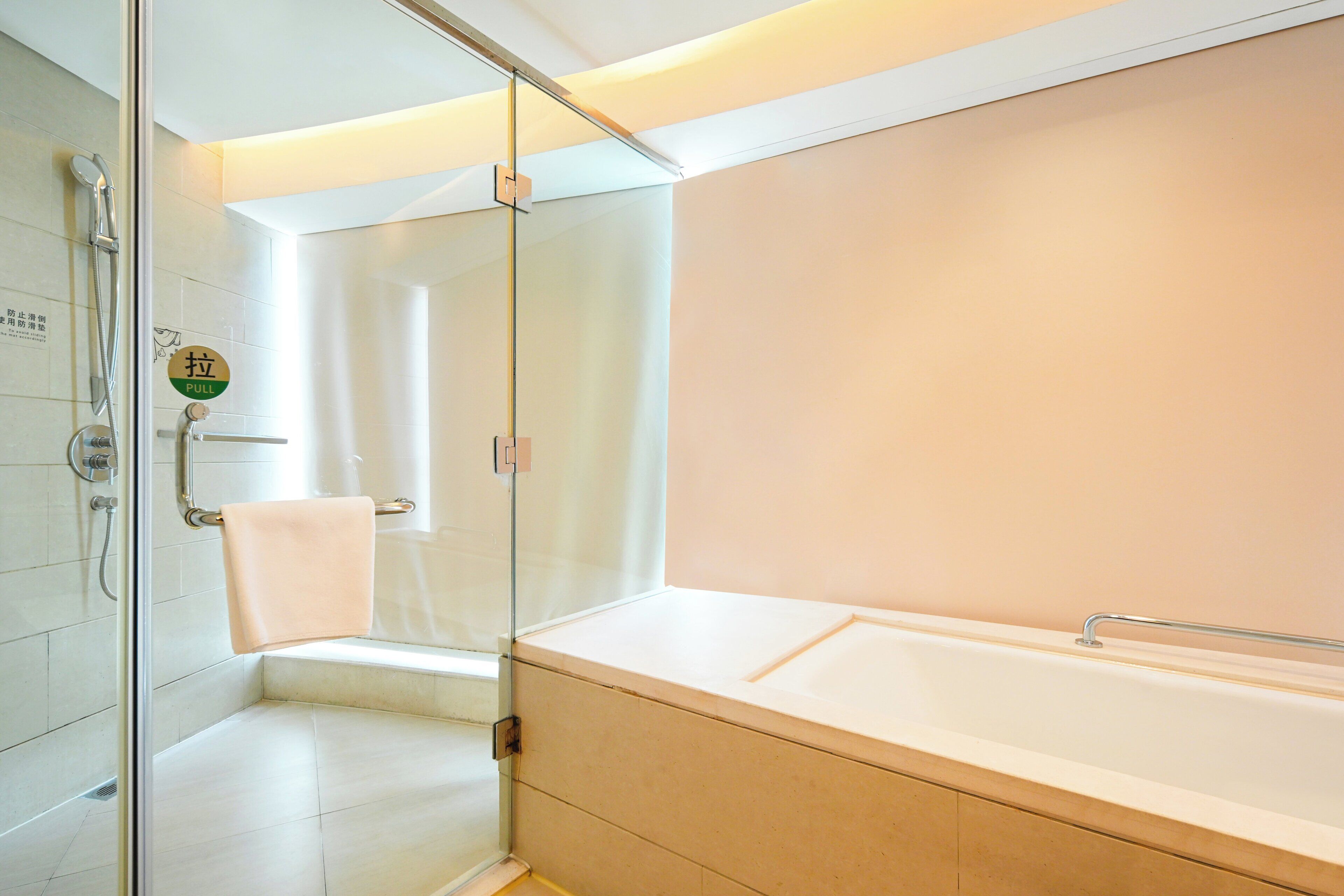 A modern bathroom with a glass shower enclosure, a bathtub, and a towel rack.
