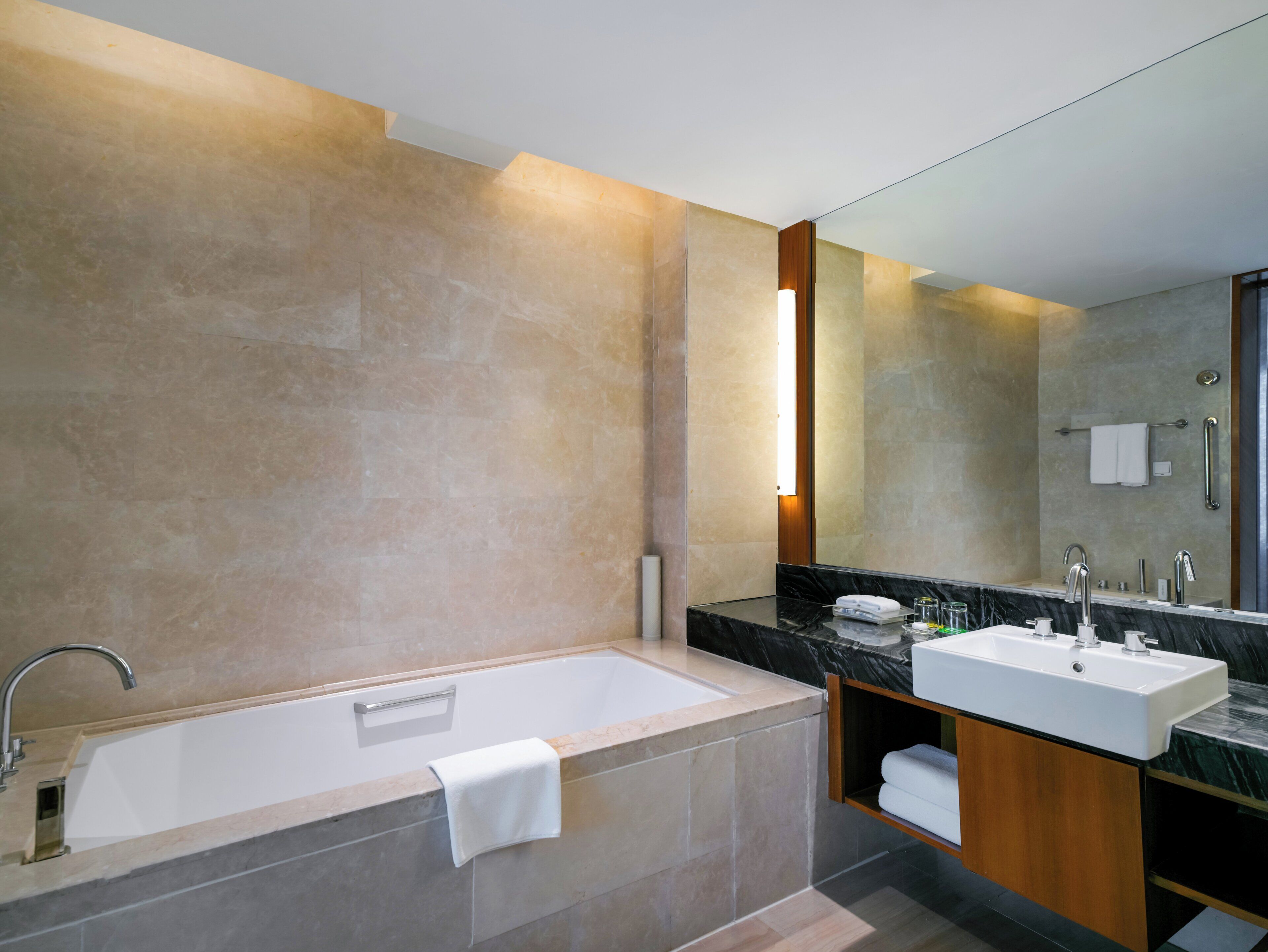 A modern bathroom with a bathtub, a vanity with a sink, and a large mirror.